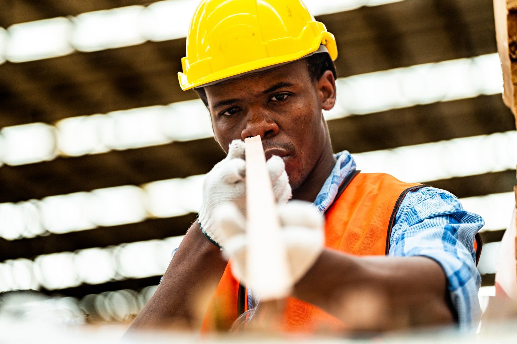 Site worker in a hard hat checking alignment along a timber batten