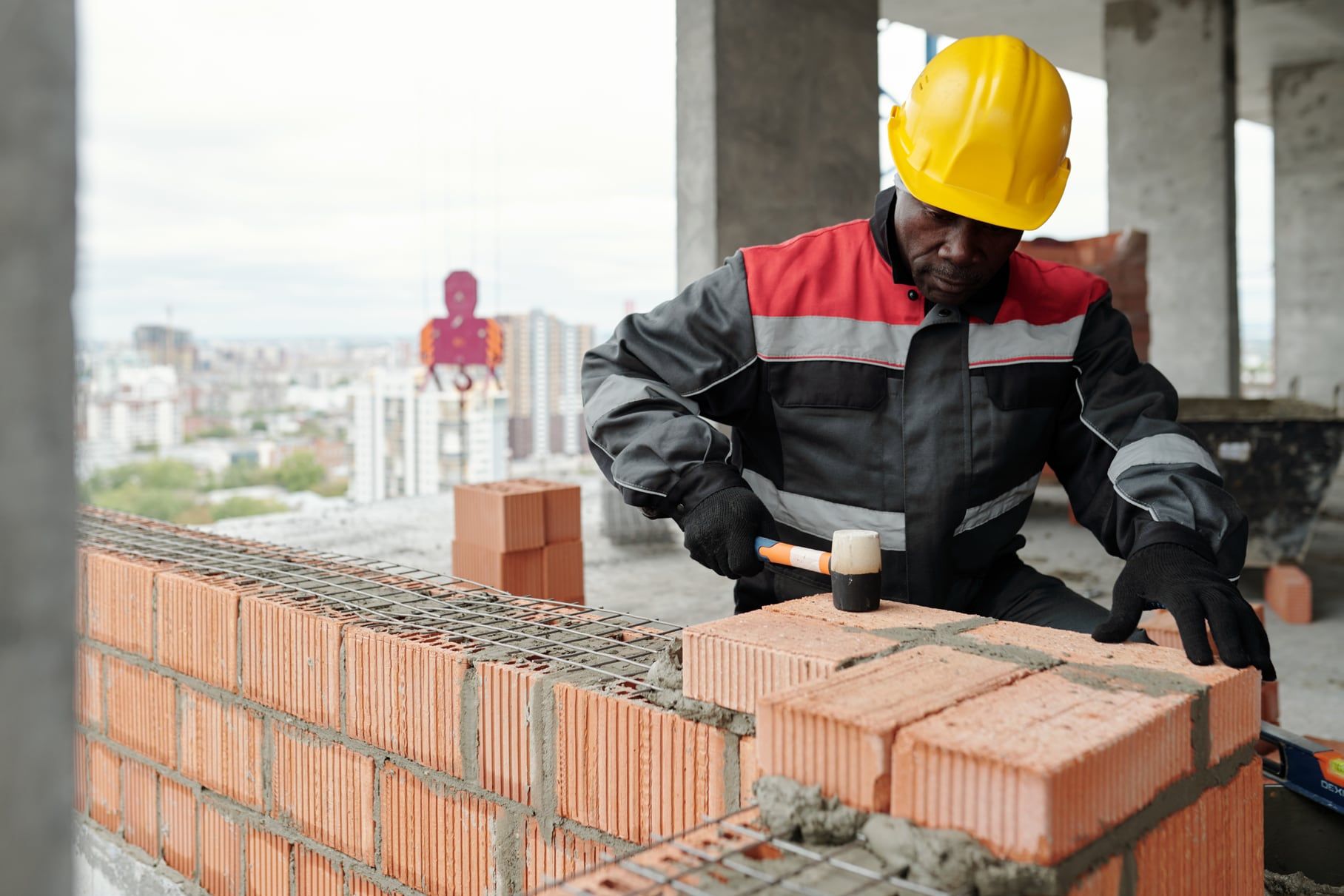 Builder in a hard hat and high-visibility jacket laying blockwork