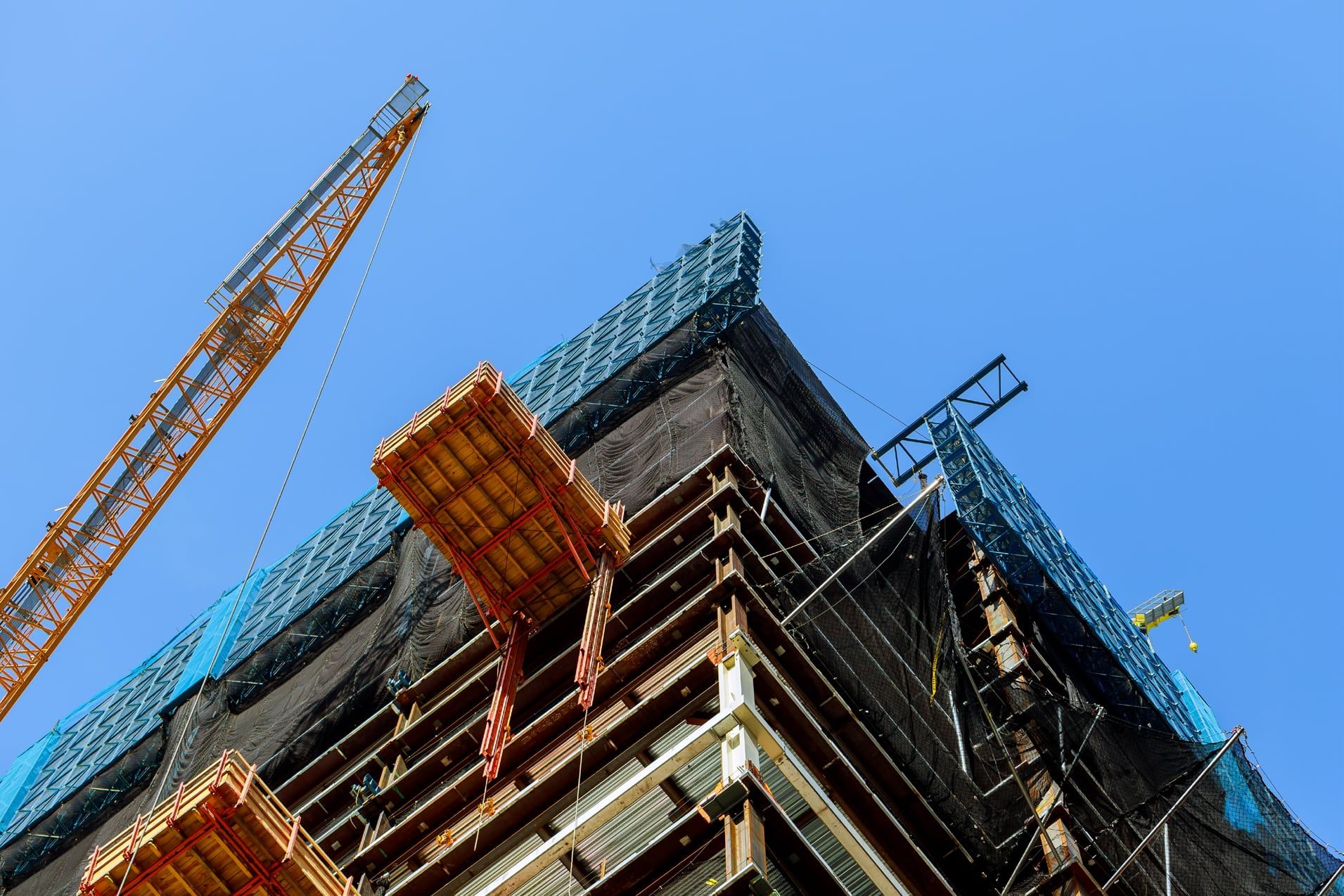 Multi-storey building under construction with scaffolding against a blue sky